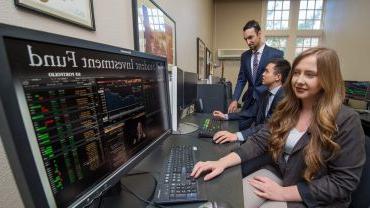 students looking at computer screens indicating financial statistics